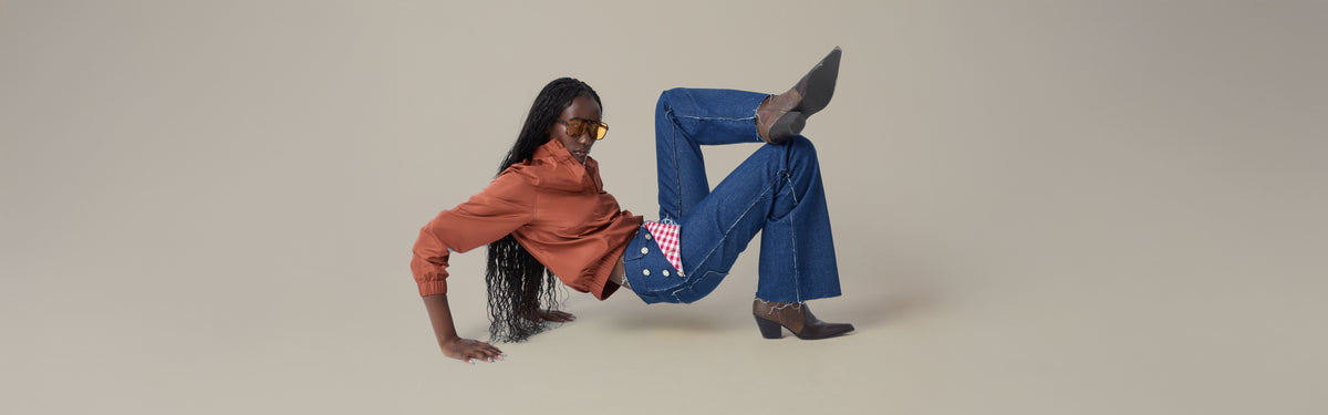 Model in Sanne dark indigo bootcut jeans with frayed hems, gold buttons and cowboy boots.